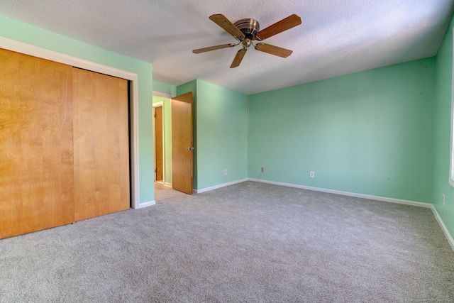 unfurnished bedroom with a textured ceiling, a closet, ceiling fan, and carpet flooring