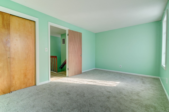 unfurnished bedroom with light colored carpet and a closet