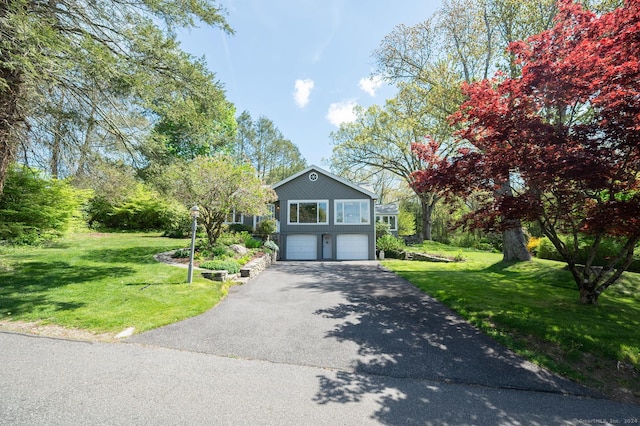 view of front of property with aphalt driveway, an attached garage, and a front yard