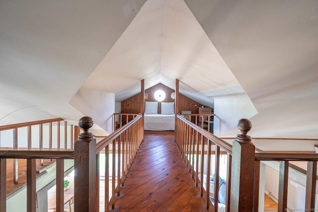 hall featuring an upstairs landing, lofted ceiling, and wood-type flooring