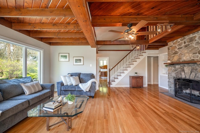 living room with wooden ceiling, a stone fireplace, light wood-style flooring, and stairs