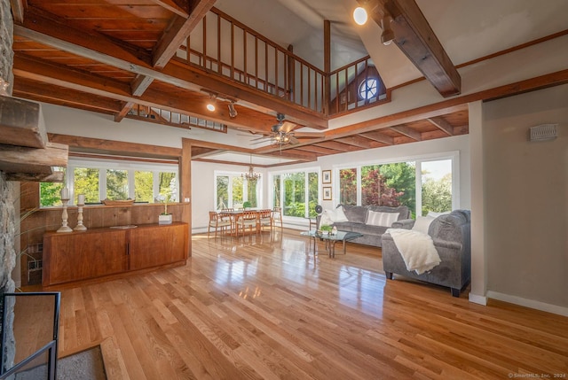 unfurnished living room featuring baseboards, beamed ceiling, rail lighting, an inviting chandelier, and wood finished floors