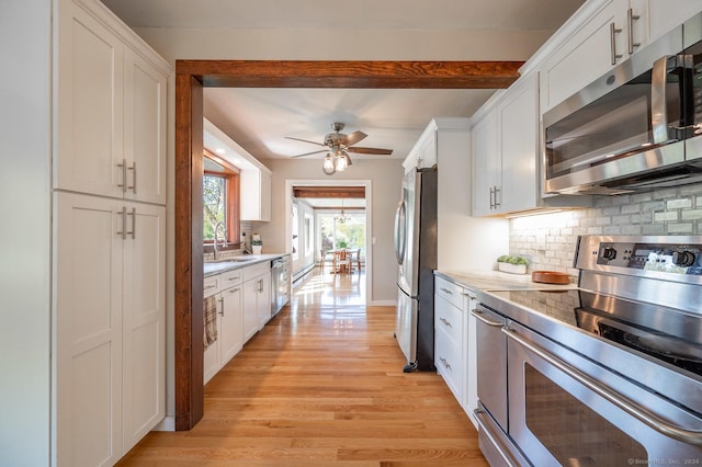 kitchen with a sink, stainless steel appliances, light wood-style floors, and white cabinetry