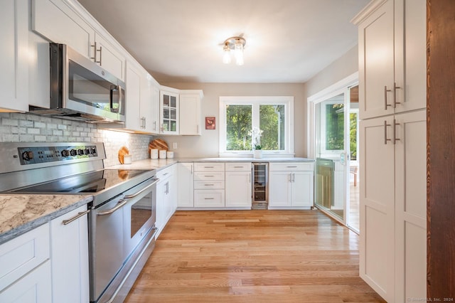 kitchen featuring stainless steel appliances, wine cooler, white cabinets, light wood-style floors, and tasteful backsplash