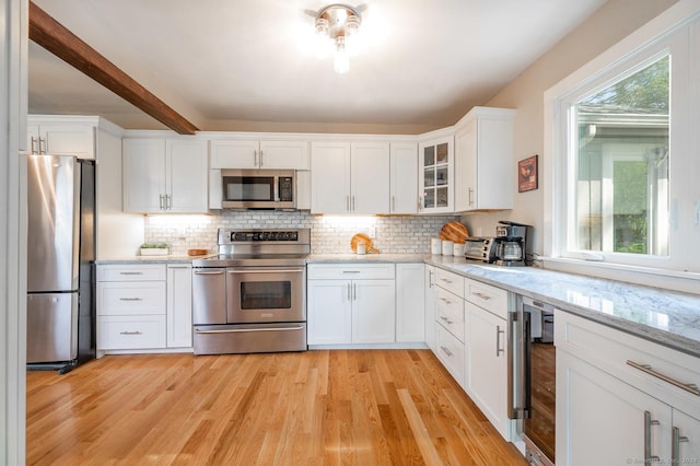 kitchen featuring wine cooler, decorative backsplash, light wood-style floors, white cabinets, and stainless steel appliances