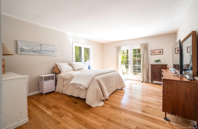 bedroom with access to exterior, light wood finished floors, and baseboards