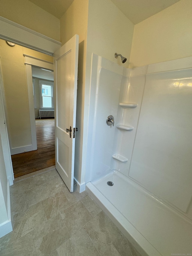 bathroom featuring wood-type flooring, walk in shower, and radiator