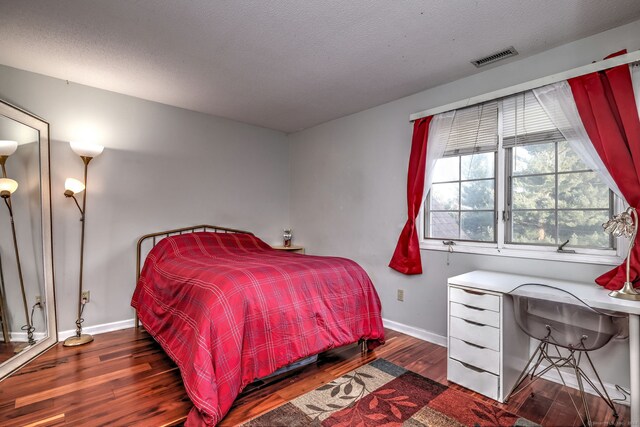 bedroom with a textured ceiling and dark hardwood / wood-style flooring