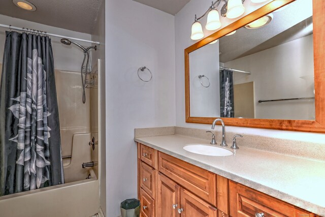 bathroom featuring a textured ceiling, vanity, and shower / bathtub combination with curtain