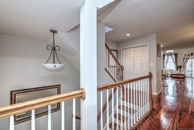 corridor with a textured ceiling and dark hardwood / wood-style flooring