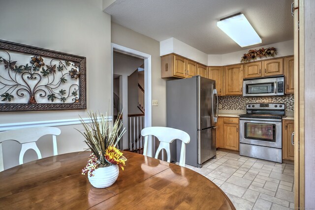 kitchen featuring a textured ceiling, backsplash, and stainless steel appliances