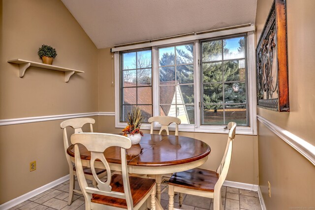 tiled dining space featuring plenty of natural light and lofted ceiling