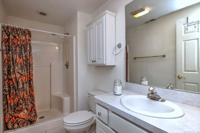 bathroom with tile patterned flooring, vanity, toilet, and walk in shower