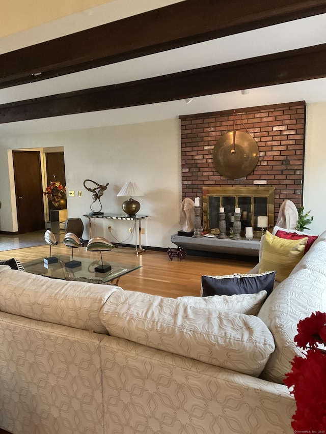 living room featuring hardwood / wood-style floors, beam ceiling, and a brick fireplace