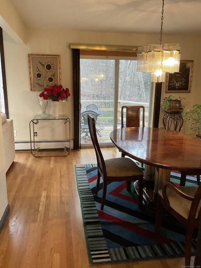 dining room with an inviting chandelier, light wood-type flooring, and a baseboard heating unit