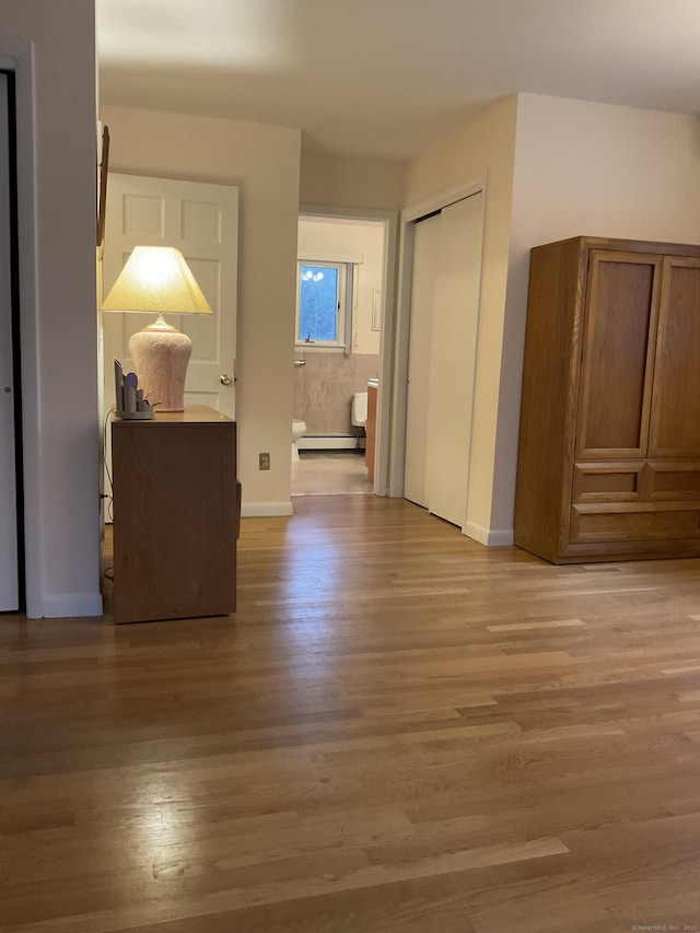 hall with a baseboard heating unit and hardwood / wood-style flooring