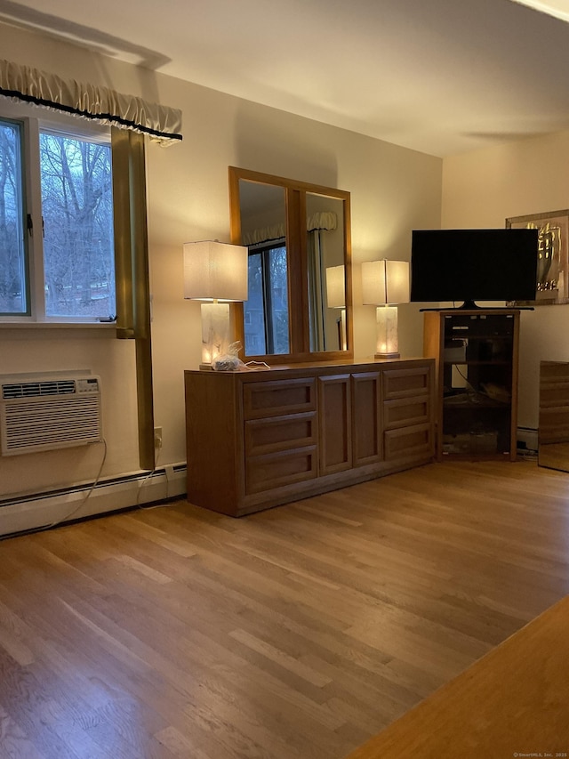 bedroom featuring light hardwood / wood-style floors, baseboard heating, and a wall mounted AC