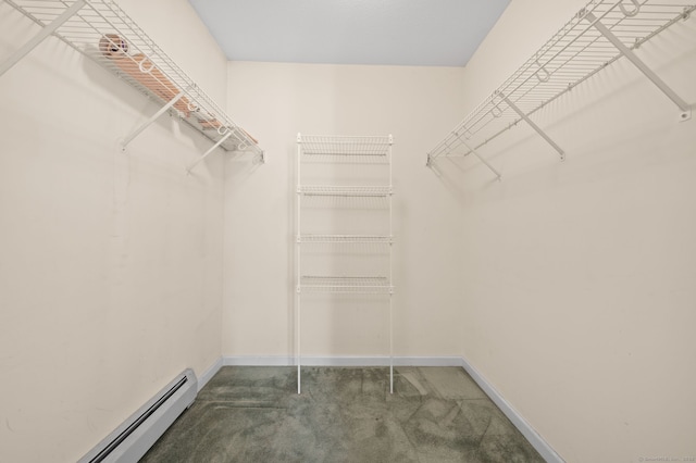 spacious closet with dark colored carpet and a baseboard radiator