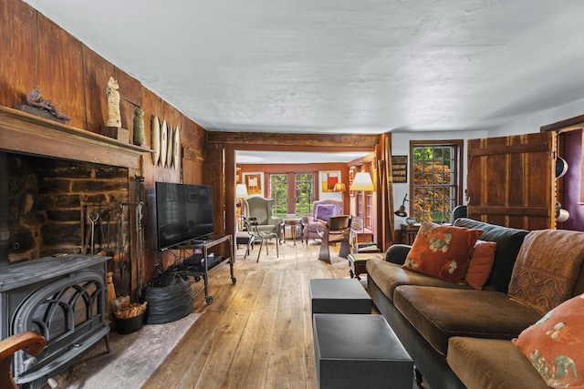 living room featuring light hardwood / wood-style floors, a wood stove, and wooden walls