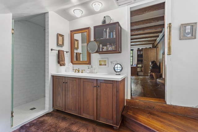 bathroom with vanity, wood-type flooring, tiled shower, and lofted ceiling