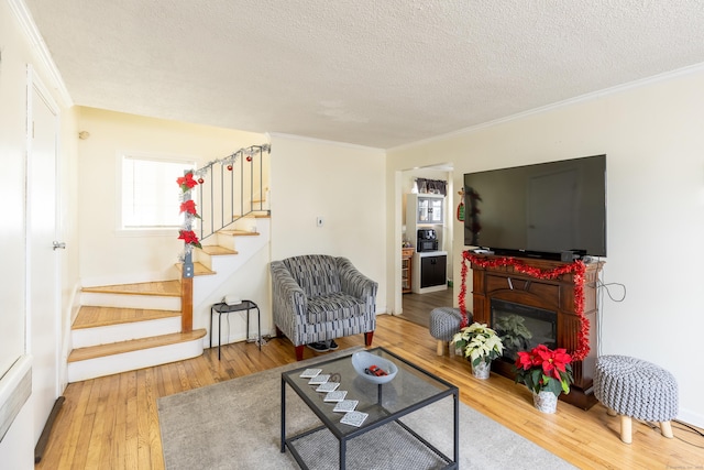 living room featuring crown molding, hardwood / wood-style floors, and a textured ceiling