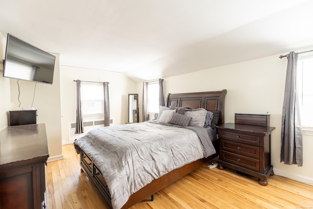 bedroom with light hardwood / wood-style floors, lofted ceiling, and multiple windows