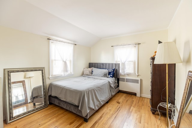 bedroom featuring radiator, vaulted ceiling, and light wood-type flooring