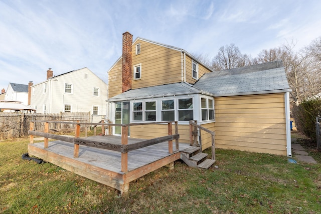 back of property with a wooden deck, a sunroom, and a yard