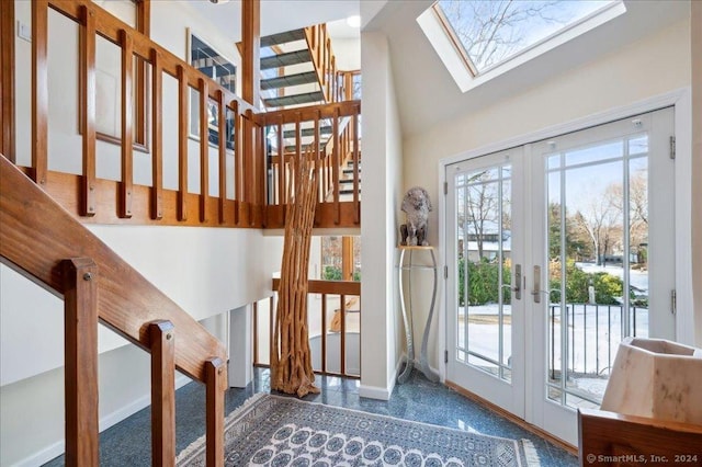 interior space with french doors, a towering ceiling, and a skylight