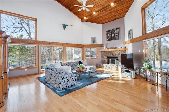 living room with ceiling fan, wooden ceiling, a premium fireplace, light hardwood / wood-style flooring, and high vaulted ceiling