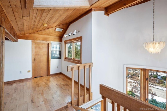 corridor featuring lofted ceiling with beams, light hardwood / wood-style flooring, wooden ceiling, and a notable chandelier