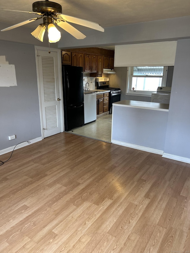 kitchen featuring dark brown cabinetry, ceiling fan, black fridge, light hardwood / wood-style flooring, and range with gas cooktop