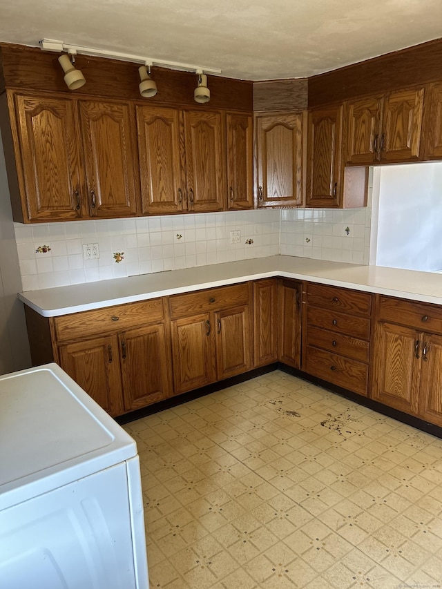 kitchen with rail lighting, washer / clothes dryer, and tasteful backsplash