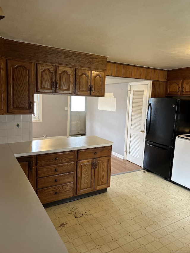 kitchen with decorative backsplash, black fridge, kitchen peninsula, and white stove