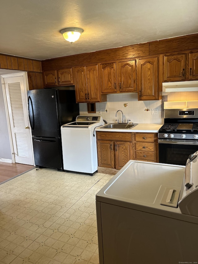 kitchen with stainless steel gas stove, washer / clothes dryer, black refrigerator, and sink