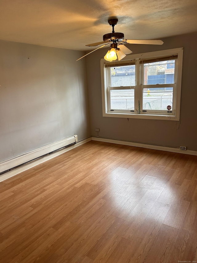 spare room with ceiling fan, light hardwood / wood-style floors, and a baseboard heating unit