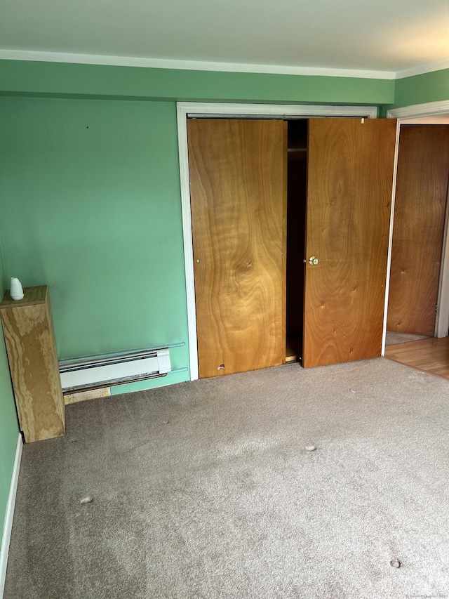 unfurnished bedroom with carpet flooring, a closet, and a baseboard heating unit