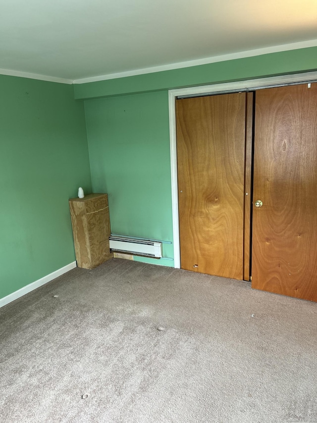 unfurnished bedroom featuring carpet, crown molding, a closet, and a baseboard heating unit