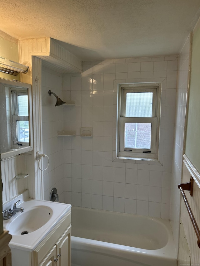 bathroom with vanity, a textured ceiling, and tiled shower / bath combo