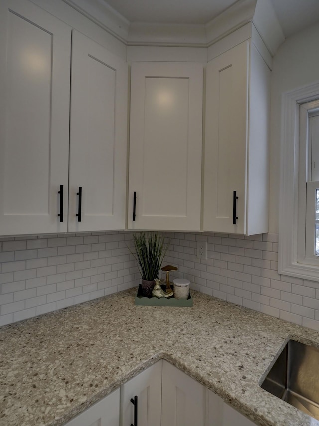 kitchen featuring white cabinetry, light stone counters, and decorative backsplash