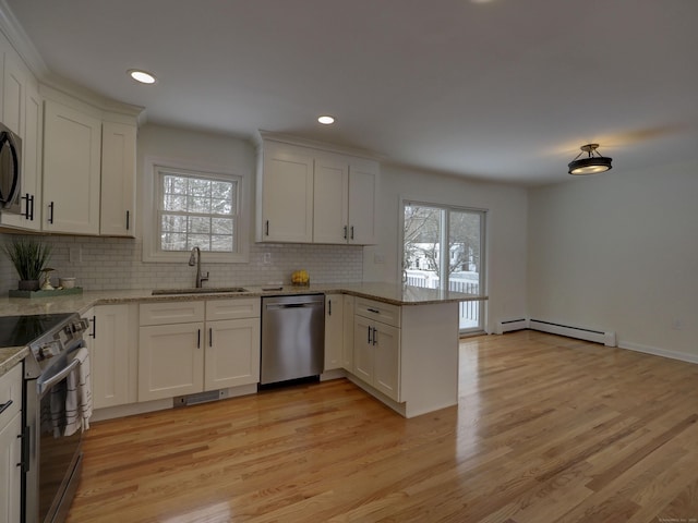 kitchen featuring sink, white cabinets, light stone counters, kitchen peninsula, and stainless steel appliances