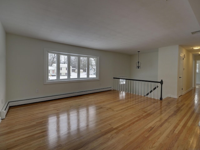 empty room featuring a baseboard radiator and light wood-type flooring