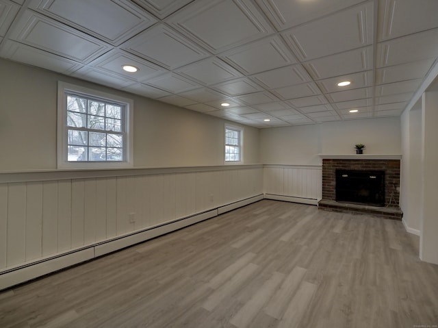 basement with hardwood / wood-style floors, a fireplace, and baseboard heating