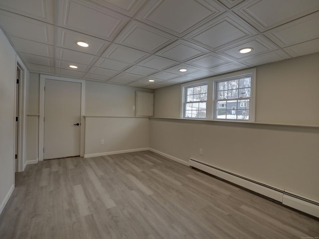 basement with light hardwood / wood-style flooring and a baseboard heating unit