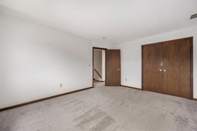 unfurnished bedroom with light colored carpet and a closet