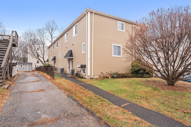 view of property exterior with central AC unit and a yard