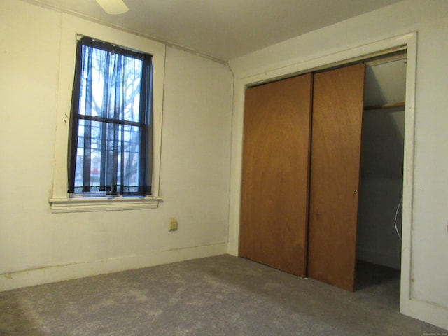 unfurnished bedroom with dark colored carpet and a closet