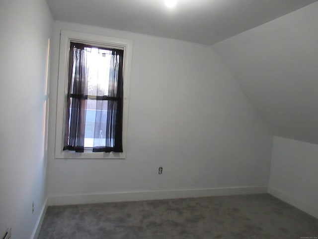 bonus room featuring vaulted ceiling and dark colored carpet