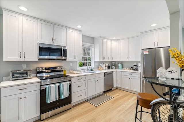 kitchen featuring white cabinets, light hardwood / wood-style floors, sink, and appliances with stainless steel finishes