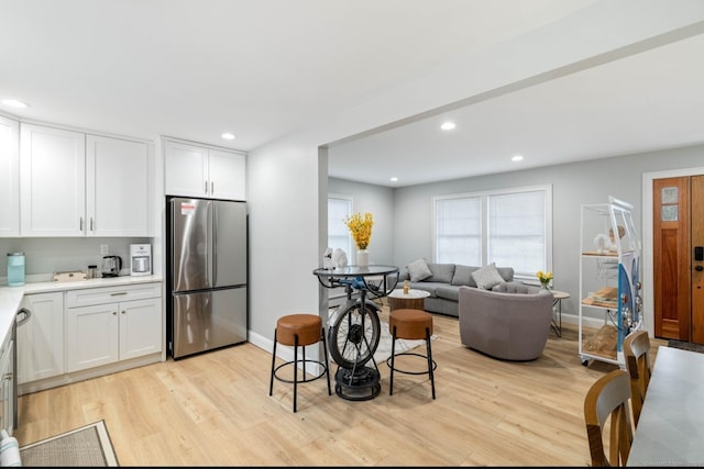 kitchen with stainless steel fridge, light hardwood / wood-style floors, and white cabinetry